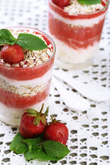Dessert with fresh strawberry, cream and granola, on color wooden table background