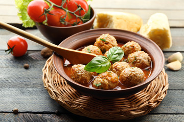 Meat balls with tomato sauce, wooden spoon on wooden background