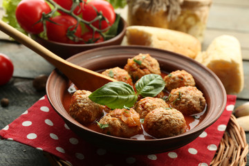 Meat balls with tomato sauce, wooden spoon on wooden background