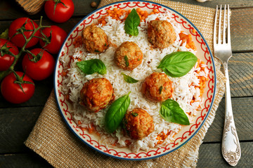 Meat balls in tomato sauce with boiled rice and lentil, wooden spoon on wooden background