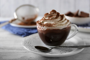 Cup of coffee with cream on color wooden background