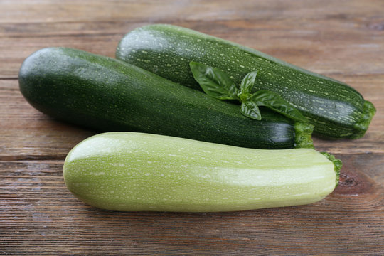 Fresh zucchini with squash and basil on wooden background