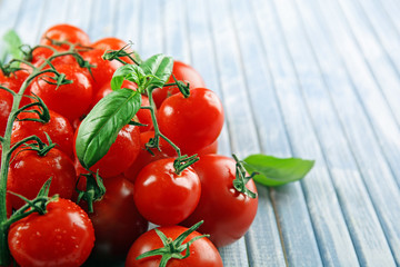 Fresh cherry tomatoes with basil on wooden table close up