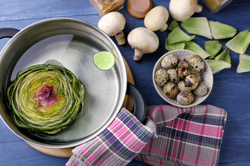 Artichokes in pan on cutting board, on  wooden background