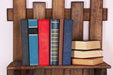Wooden shelf with books on wall, closeup