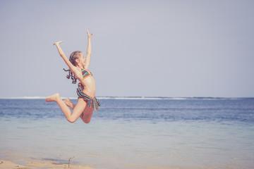 teen girl  jumping on the beach at blue sea shore in summer vaca
