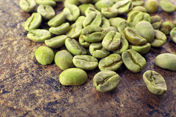 Heap of green coffee beans on table close up