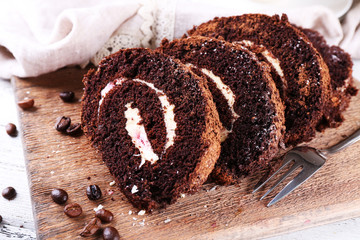 Delicious chocolate roll on wooden cutting board, closeup