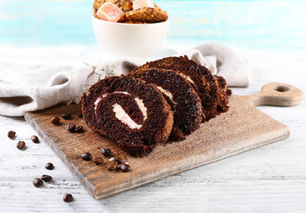 Delicious chocolate roll on cutting board on wooden background