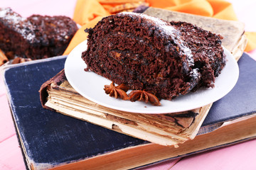 Delicious chocolate roll in saucer on book, closeup