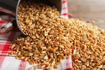 Gordijnen Cup of wheat grains on wooden table with napkin, closeup © Africa Studio