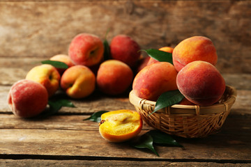 Ripe peaches in basket on wooden background