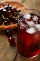 Glass of cherry juice on wooden table, closeup