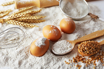 Wheat and eggs on white flour background