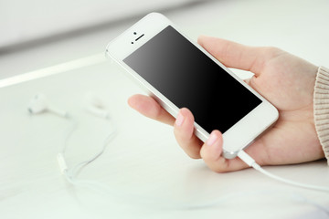 Music smartphone in female hand, on light background