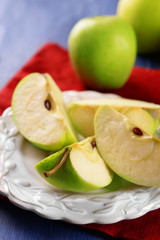 Pieces of green apple in saucer on wooden table with napkin, closeup