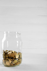 Coins in money jar on wooden background