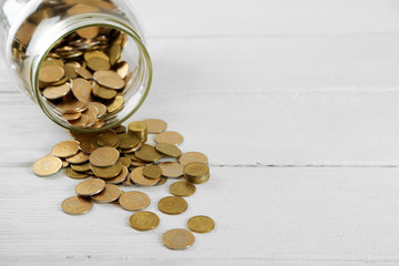Coins in money jar on wooden background