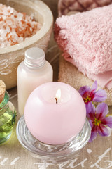 Pink scented candle, soft towels and bowl of sea salt