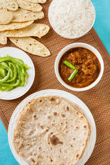 Mutton rogan josh meal - Overhead view of Indian mutton rogan josh meal with rice and chapati. This spicy hot Kashmiri dish uses red chilli (cayenne pepper) as its main ingredient. Natural light used.