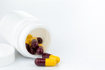brown and yellow pills an pill bottle on white background