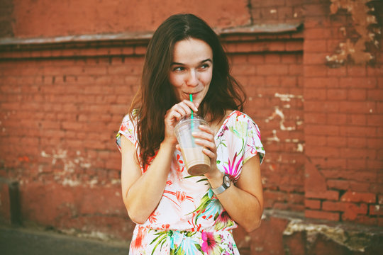 pretty smiling girl with milk shake on brick wall background