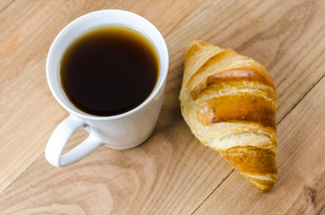 Breakfast cup of coffee and croissant.