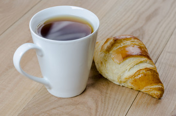 Breakfast cup of coffee and croissant.