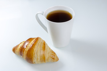 Breakfast cup of coffee and croissant.