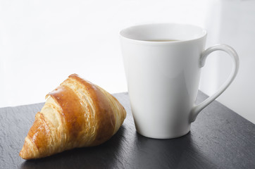 Breakfast cup of coffee and croissant, horizontal.