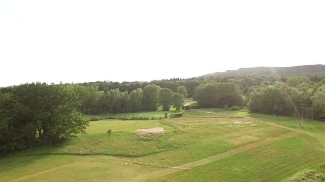 Drone flying around a golf course on a sunny day.