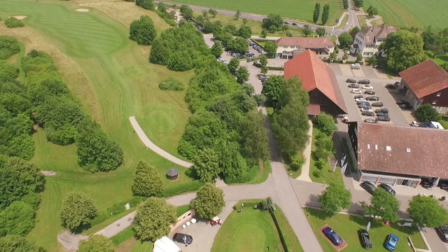 Aerial perspective of a golf course and a club house filmed by a rotating drone