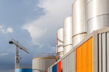 The big petrol oil tanks and hoisting crane againt blue sky in r