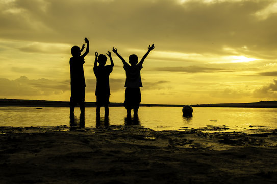 image silhouette boys rise their hand and ball on the ring during sunset sunrise, reflection on water