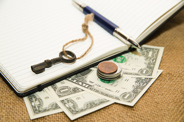 Opened notebook, pen, key and money on the old tissue