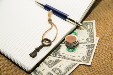 Opened notebook, pen, key and money on the old tissue