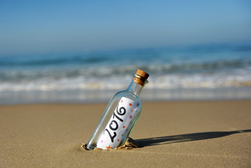 New year party, bottle with message on the beach, 2016