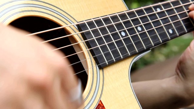 Close up to playing acoustic guitar