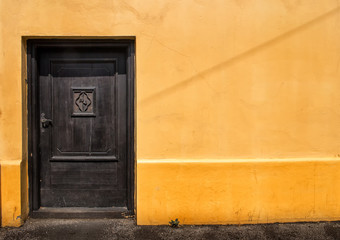 Obraz na płótnie Canvas Dark Door in an Orange Wall