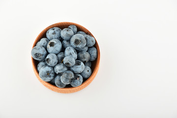 Handful of blueberries in wooden bowl isolated on white