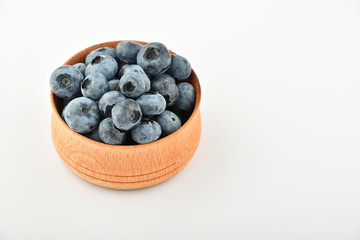 Handful of blueberries in wooden bowl isolated on white