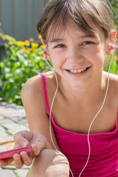 Cute little girl in headphones listening to music in the garden