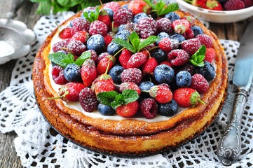 Cottage cheese casserole with fresh strawberries, blueberries, raspberries and mint and powdered sugar