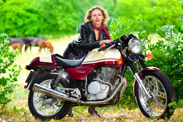 Biker girl in leather jacket on a motorcycle against the
