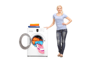 Young woman standing next to a washing machine