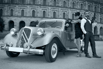 Verbrecher Paar mit Oldtimer und Waffe in schwarz weiß Porträt
