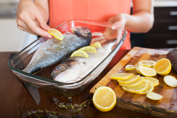 Close-up of woman putting pieces of lemon in fish