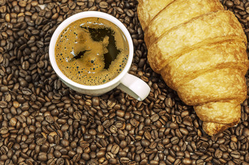 Coffee bean background with cup of fresh hot coffee and croissan