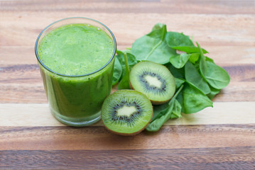 green smoothie with fresh spinach and kiwi on wood