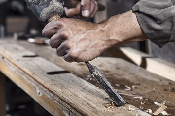 Hands of carpenter with chisel in the hands - obrazy, fototapety, plakaty